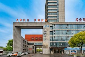 鎮江市にあるUrba Hotel, Danyang Technical Secondary School, Municipal Traditional Chinese Medicine Hospitalの建物の前に車が駐車されている