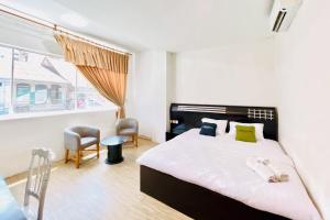 メダンにあるUrbanview Hotel Grand Mohaga Medanのベッドと椅子2脚と窓のある寝室