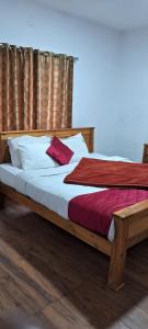 a bedroom with a wooden bed with white and red pillows at Key2Heaven in Ooty