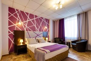 Habitación de hotel con cama y pared púrpura en Marton Turgeneva Krasnodar, en Krasnodar