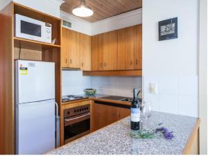 a kitchen with a white refrigerator and a bottle of wine at Cora Lynn - Apartment 18 in Lorne