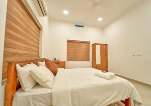 a bedroom with a bed with a wooden headboard at Ashtamudi Lake Villa by VOYE HOMES - Pet Friendly & Events Welcome in Kollam
