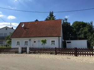 una casa bianca con un tetto rosso dietro una recinzione di Ilmhaus a Pförring