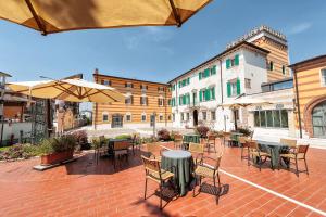 un patio al aire libre con mesas, sillas y sombrillas en Hotel Villa Malaspina, en Castel d'Azzano