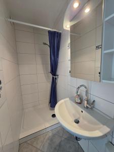 a white bathroom with a sink and a shower at Vier Jahreszeiten 5-2 in Großenbrode-Kai
