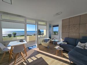 a living room with a blue couch and a view of the ocean at Vier Jahreszeiten "Strandglück" im Haus 2 Wohnung 45 in Großenbrode-Kai