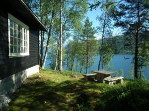 a picnic table and bench next to a lake at Haukedalen Hytter in Viksdalen