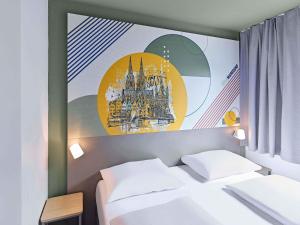 a room with a bed and a painting on the wall at B&B HOTEL Köln-Marsdorf in Cologne