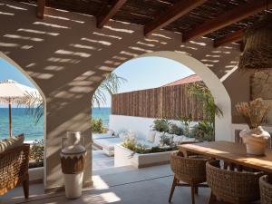Un patio con mesa y sillas y el mar. en Oriana, Beachfront villa, en Zakynthos