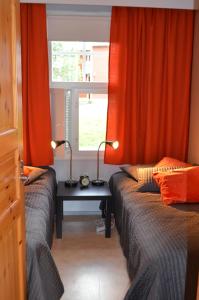2 Betten in einem Zimmer mit orangefarbenen Vorhängen und einem Tisch in der Unterkunft Castillo Moitakuru in Saariselkä