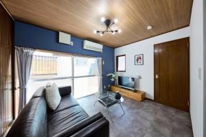 a living room with a leather couch and a tv at 成田空港から31分で駅徒歩8分富士桜侍3ldk 63平米 最大8人静か in Matsudo