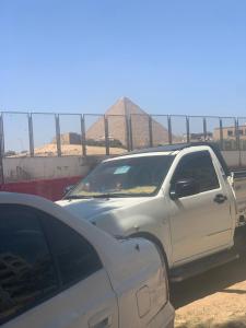 a white truck parked in front of a pyramid at Golden Sand Pyramids in Cairo