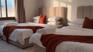 a bedroom with two beds with white sheets and orange pillows at Gulfa 9 in Sinādil