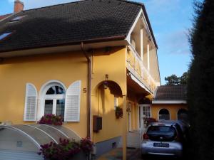 a yellow house with a car parked in the driveway at Ilona Vendégház in Siófok