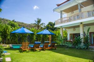 un patio con sillas y sombrillas junto a una casa en The Raka Villa Amed, en Amed