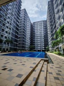 マニラにあるCabin and a cozy stay near MOAの2棟の高い建物の前にスイミングプールがある大きなアパートメント複合施設です。