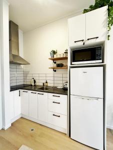 a kitchen with a white refrigerator and a microwave at Skytower views, Wi-Fi, washer & dryer!! in Auckland