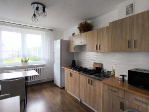 a kitchen with wooden cabinets and a sink and a refrigerator at Agroturystyka Tęczowa Dolina in Bodzentyn