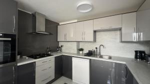 a kitchen with white cabinets and a sink at Modern House with four BR two parking bays in Bolton in Bolton