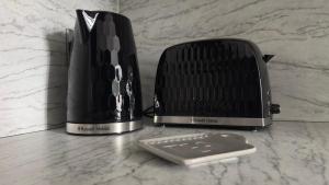 a cell phone sitting next to a toaster on a counter at Modern House with four BR two parking bays in Bolton in Bolton +25 photos