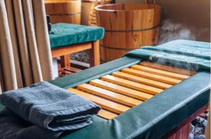 a bed with a green sheet and a towel on it at Ngải Spa, Body, Foot Massage in Hanoi