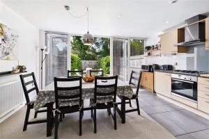 eine Küche mit einem Tisch und Stühlen in einer Küche in der Unterkunft 3 bed modern townhouse with self check in, sleeps 6, 35mins direct train to London Waterloo, zone 6 in Ewell