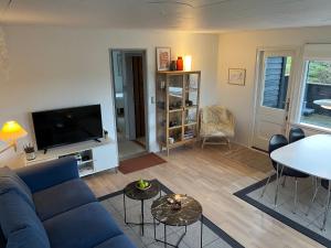 a living room with a blue couch and a tv at 60m2 sommerhus LokkenBlokhus Denmark in Løkken +7 photos