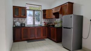 a kitchen with wooden cabinets and a stainless steel refrigerator at Villa 19 Zone 2 Millennium City - Jaela in Ja-Ela