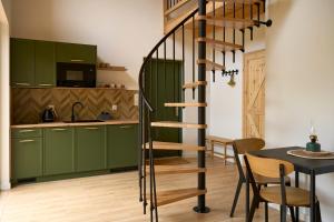 a kitchen with green cabinets and a spiral staircase at Osada Iwiec-Karpaty w Borach Tucholskich in Iwiec