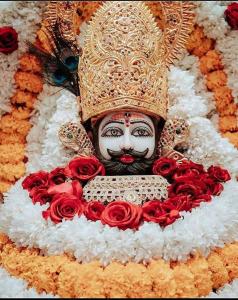 a cake with a statue of a mask and roses at Shri Ram Lala Palace in Jāmb
