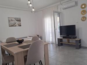 a dining room with a table and a television at SunWaves Apartments in Keramotí