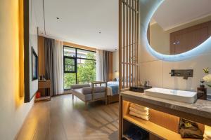a bathroom with a sink and a bed and a mirror at Zhangjiajie Gui Yuan Hotel - Free delivery to the East Gate once--service washing machine with drying, luggage storage-over 4 nights and get one free airport pick-up in Zhangjiajie