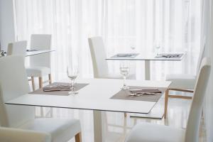 a white dining room with white chairs and tables with wine glasses at Ambra Hotel Cattolica in Cattolica
