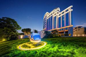 a building with a chair in the grass in front of it at Guangzhou Elegant International Hotel Panyu Square Metro Station Branch - Free Shuttle Bus to Canton Fair Complex During Canton Fair Period & Free Deliver Service to Guangzhou Baiyun International Airport in Guangzhou