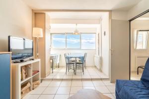 a living room with a table and chairs and a television at Les Balcons de la Méditerranée in Narbonne-Plage