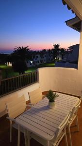 a table and chairs on a balcony with the sunset at Apartamento con terraza y vistas al mar en Son Bou in Son Bou