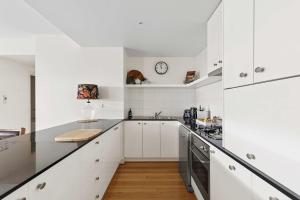 eine Küche mit weißen Schränken und einer Uhr an der Wand in der Unterkunft Waterfront Premium Apartment in central Geelong in Geelong