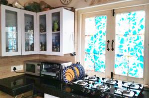 Una cocina con estufa y microondas y ventanas. en Rumis Mountain Sunset, en Nainital