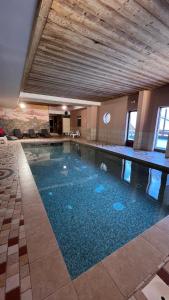a large swimming pool with blue water in a building at Appartement cosy 5-6p aux pieds des pistes 2 chambres 2 sdb in Oz