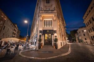 a building with tables and chairs on a street at night at HT6 Hotel Roma in Rome