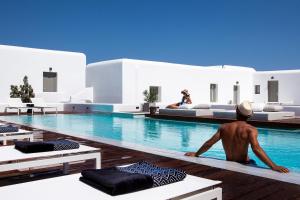 a man sitting on the edge of a swimming pool at Amyth of Mykonos Super Paradise in Super Paradise Beach