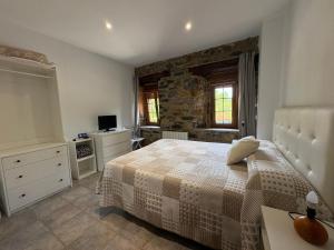 a bedroom with a bed and a stone wall at Agroturismo Gure Naia in Carranza +25 photos