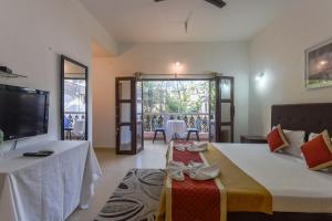 Cette chambre comprend un lit, une télévision et une table. dans l'établissement Grande Ave Maria Resort, à Candolim