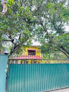 a green fence with a yellow train behind it at Dean House in Hikkaduwa +2 photos
