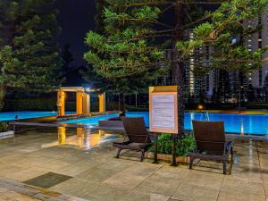 two chairs and a sign in front of a swimming pool at Condo in Tagaytay - AB Residences in Tagaytay