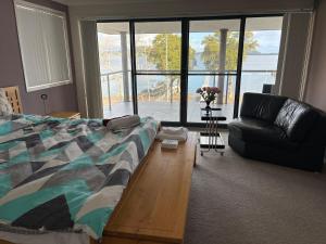 a living room with a bed and a couch at Bluewatersanctuary holiday house in Tascott +34 photos