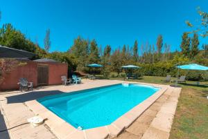 a swimming pool in a yard with umbrellas at Domaine Plan Des Devens Tendresse in Roussillon