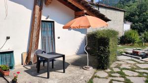 an orange umbrella sitting next to a table and a chair at ViviMontagna Livienne in Perosa Argentina