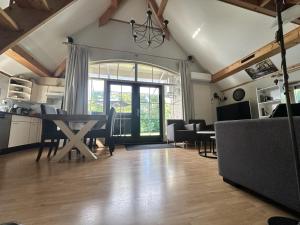 une cuisine et un salon avec une table et des chaises dans l'établissement Recreational cottage with lots of privacy, large forest garden!, à IJhorst