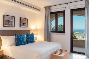 a bedroom with a bed with blue pillows and a window at La Tiara di Cervo in Liscia di Vacca